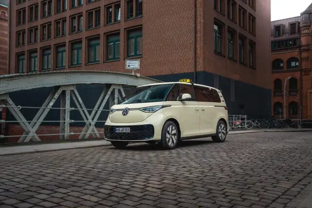 Der Volkswagen ID. Buzz-Taxi fährt über eine Brücke im Stadt-Industriegebiet. Aufgenommen zeigt der linke Seite.