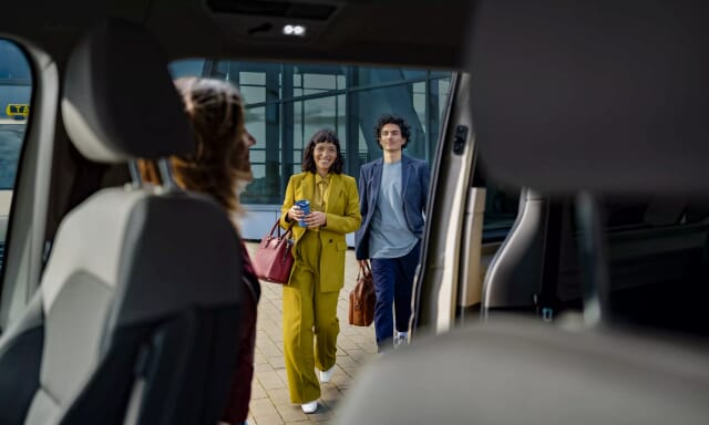 Zwei Fahrgäste, die in ein VW Multivan T7 einsteigen. Die Ansicht wird von Fahrzeuginnen durch die Schiebenture aufgenommen.