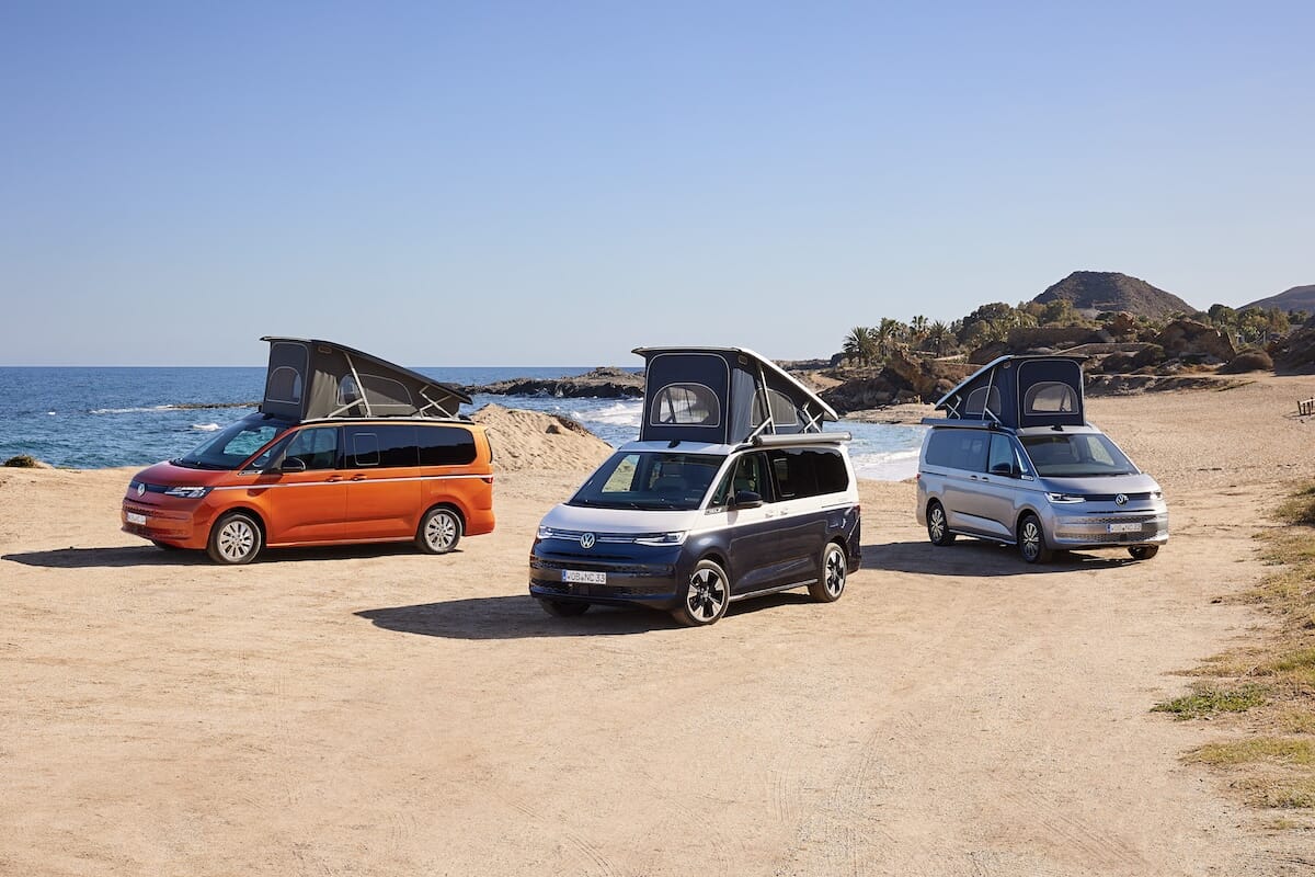 Drei neue Volkswagen California mit Aufstelldach an einem Sandstrand am Ozean. Modelle: Beach (links), Ocean (Mitte), Coast (rechts).