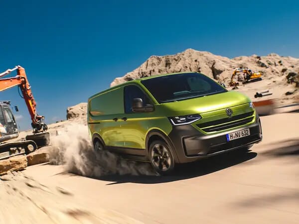 Neuer Volkswagen Transporter T7 2024 in warmgrün metallic, der durch eine Baustelle fährt und dabei Staub aufwirbelt.