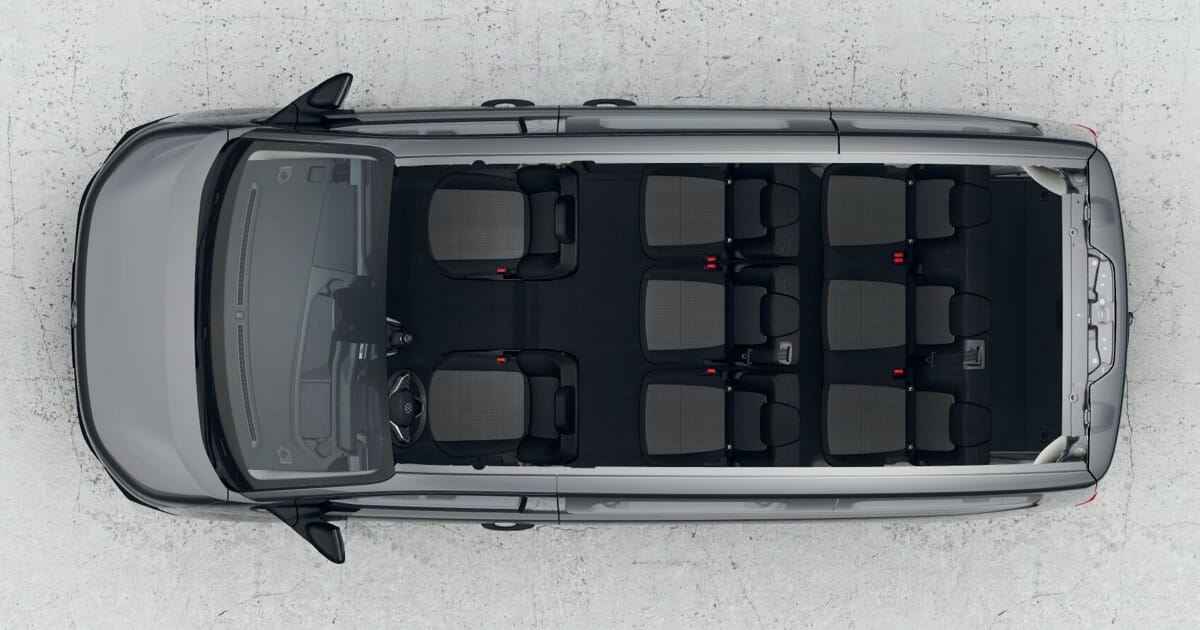 Volkswagen Caravelle T7, Innenansicht von oben mit Sitzkonfiguration für neun Personen, geräumiger Innenraum für komfortablen Personentransport.