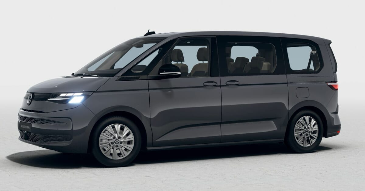 Dunkelgrauer Volkswagen Multivan T7 eHybrid in dreiviertel-frontaler Ansicht vor einem neutralen Hintergrund. Der Van hat ein modernes Design mit LED-Scheinwerfern, großen Fenstern und einem geräumigen Innenraum mit sichtbaren beigen Sitzen.