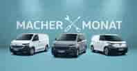 Drei Volkswagen Nutzfahrzeuge vor hellblauer Wand mit Aufschrift 'Macher Monat' und Werkzeug-Symbol: weißer E-Transporter, grauer Transporter und weißer ID. Buzz Cargo mit schwarzem Stoßfänger.