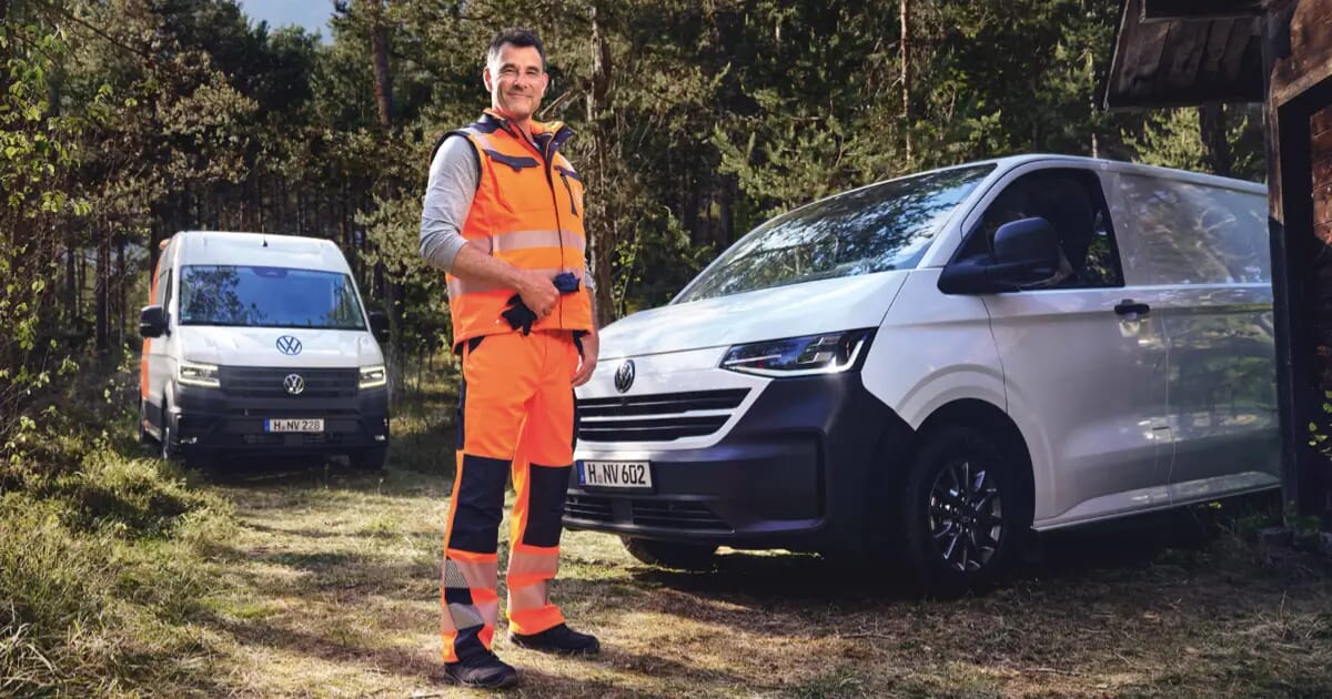 Mann in Warnkleidung steht vor Volkswagen Transporter, im Hintergrund ein Crafter im Wald.