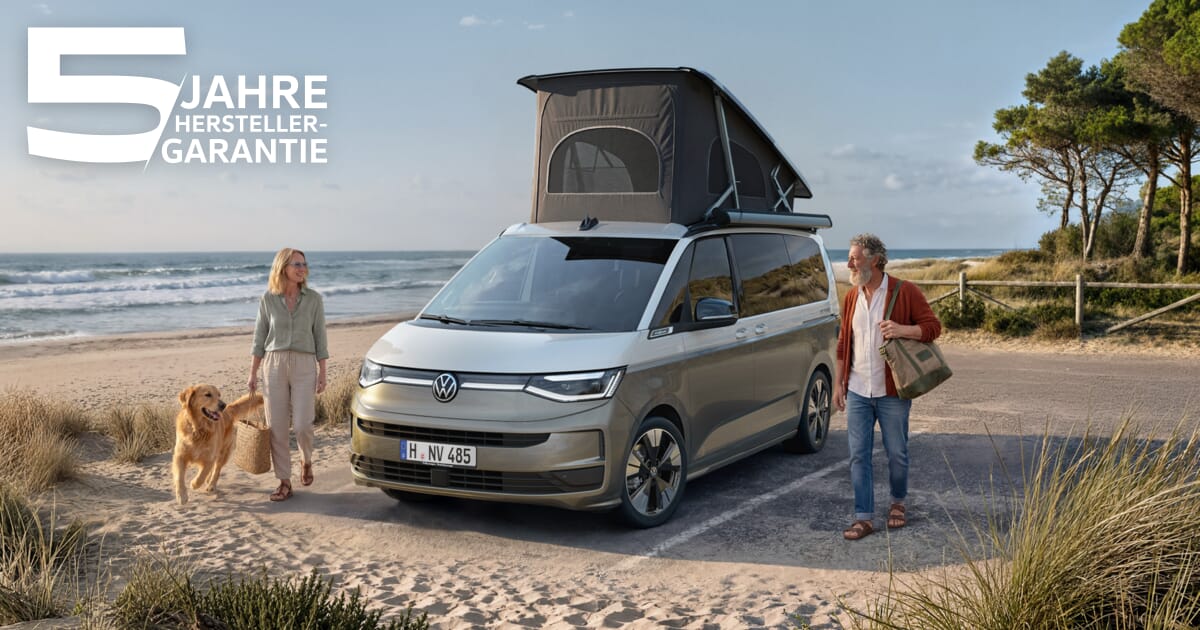 VW California Ocean am Strand mit aufgeklapptem Aufstelldach, Paar und Hund neben dem Camper.