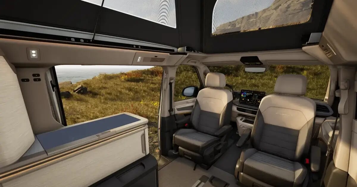 Innenraum des VW California Ocean Generation mit drehbaren Vordersitzen, Küchenzeile und geöffnetem Aufstelldach.